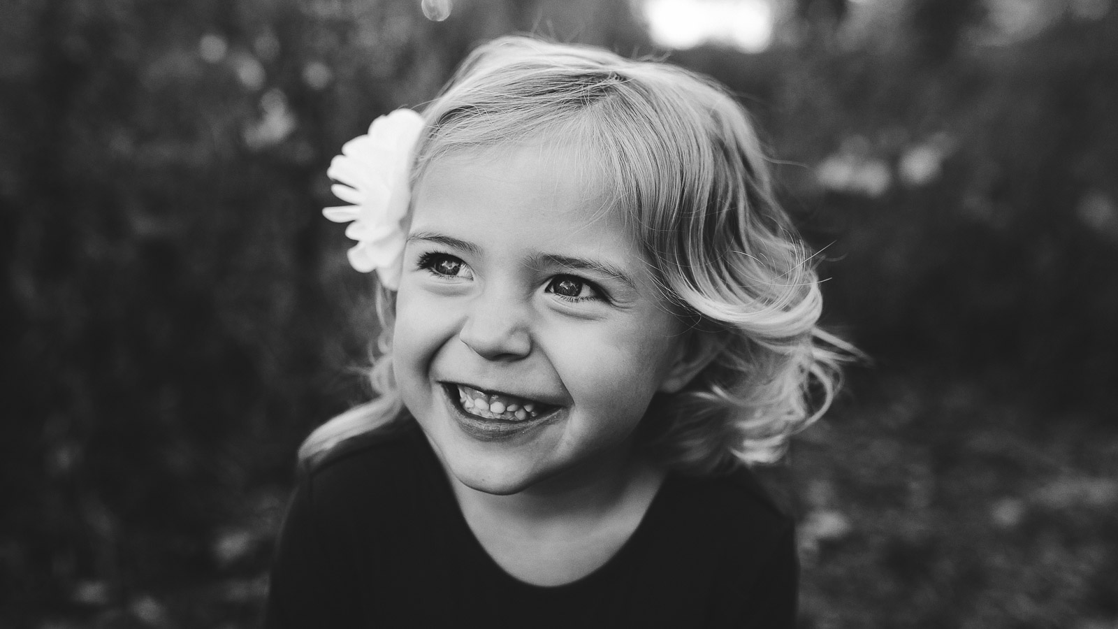 black and white photograph of a young girl smiling outdoors.