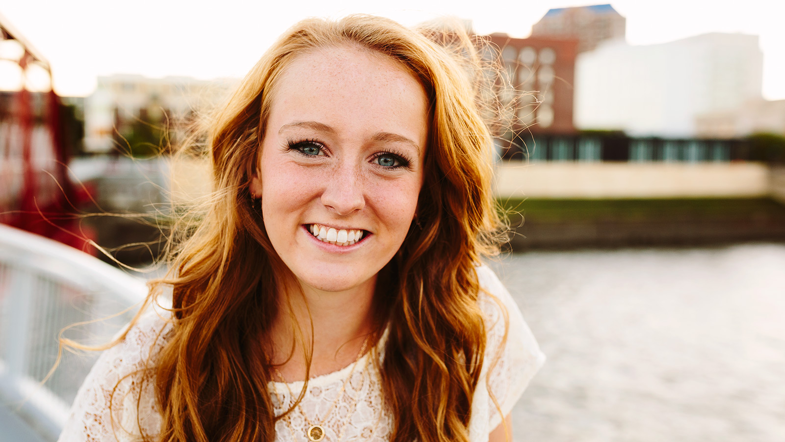 photograph of a red headed senior girl on a red bridge in the east village of des moines