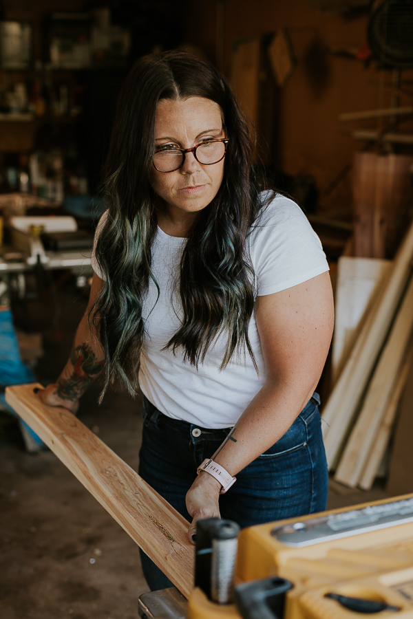 environmental headshot of a woodworker in her woodshop as she creates a piece of furniture